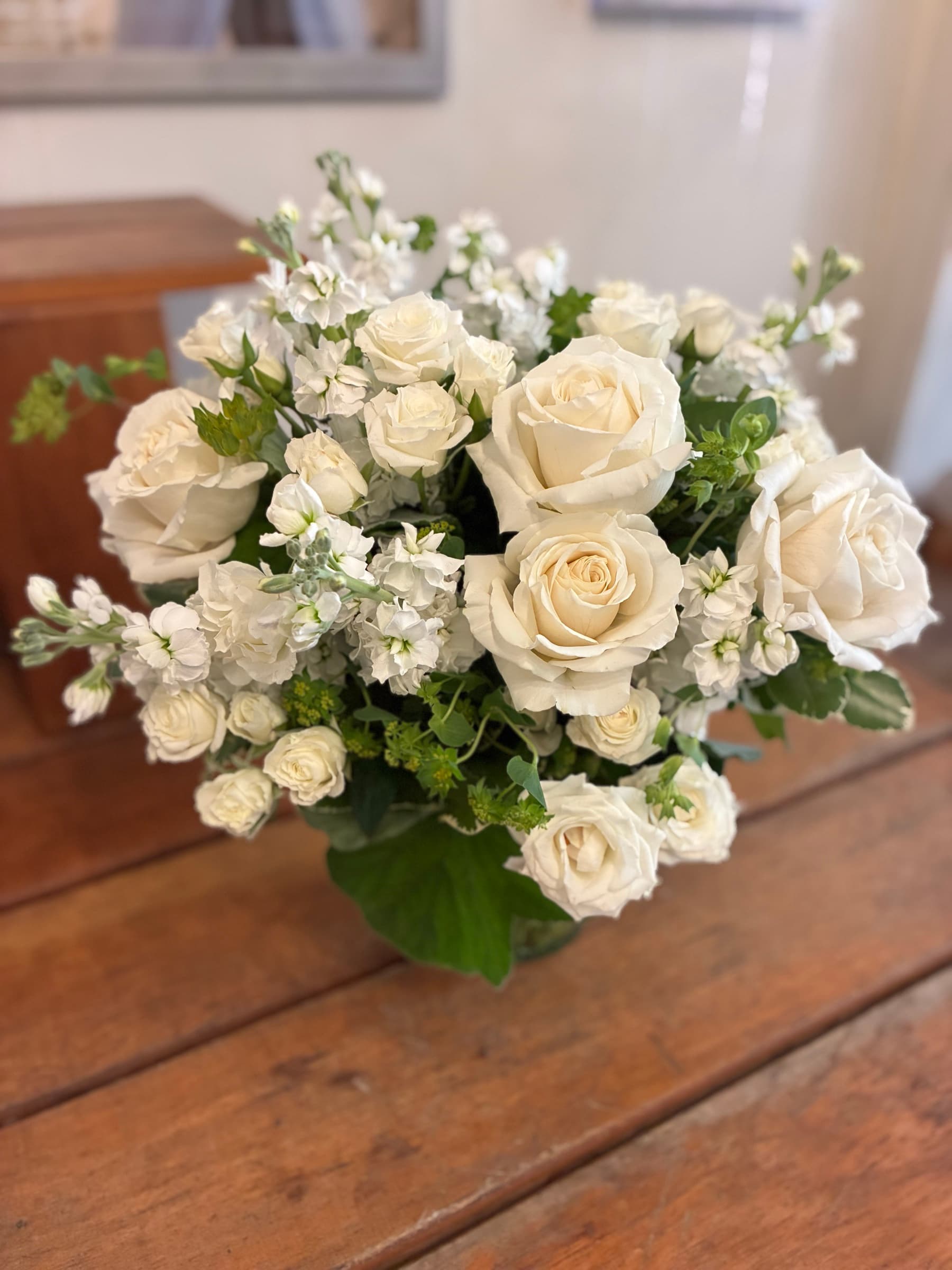Ivory garden roses and white stock in a low vase
