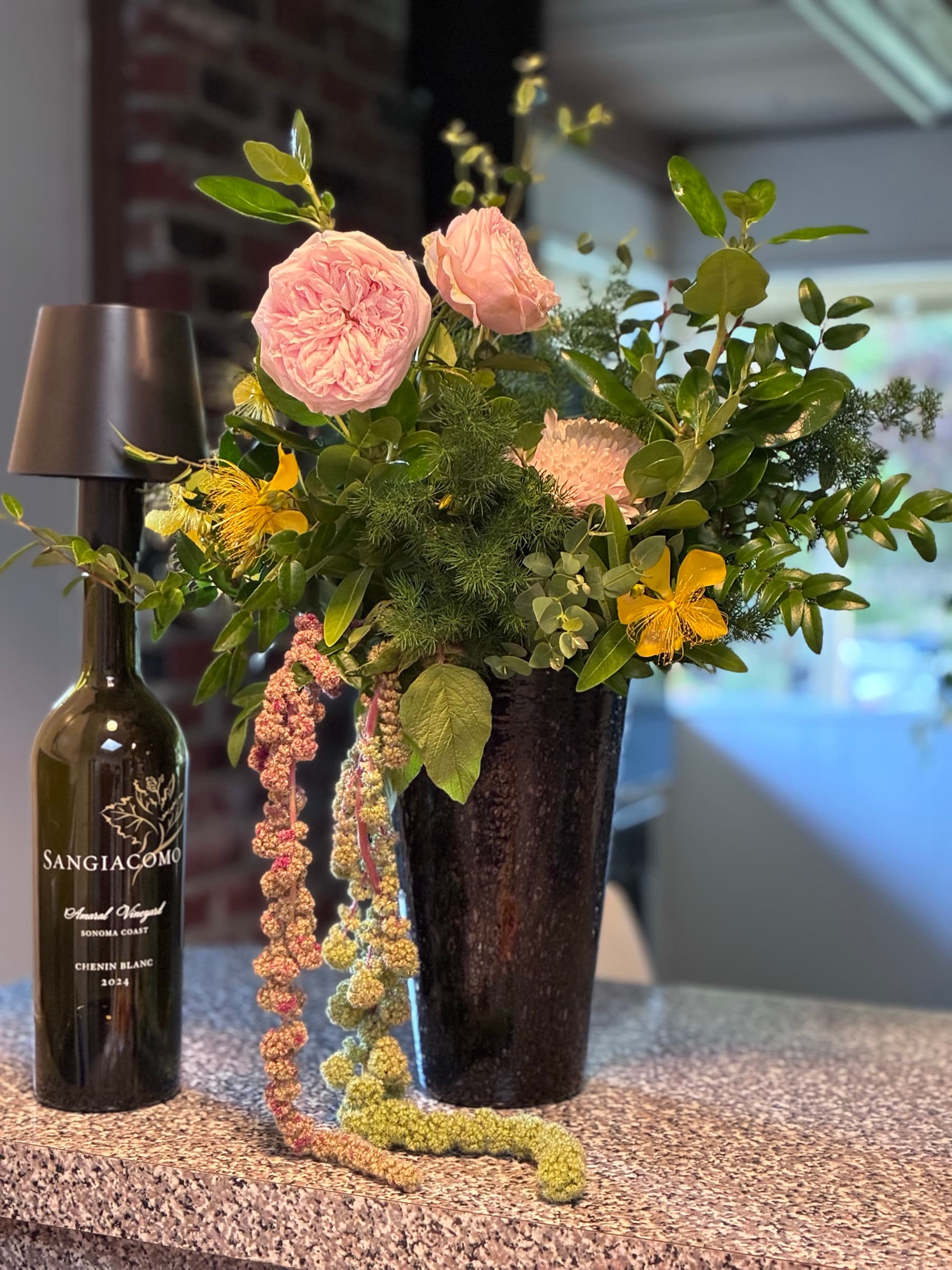 Garden roses and trailing amaranthus beside a bottle of wine