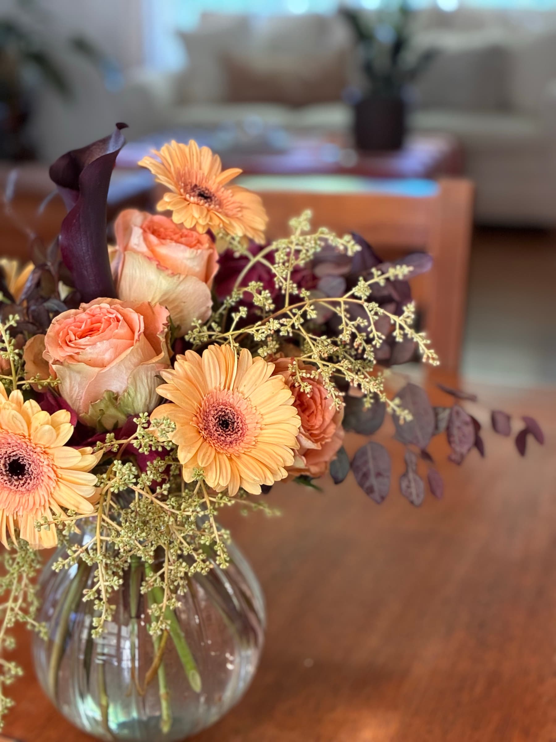 Peach gerbera and roses in a glass bubble vase