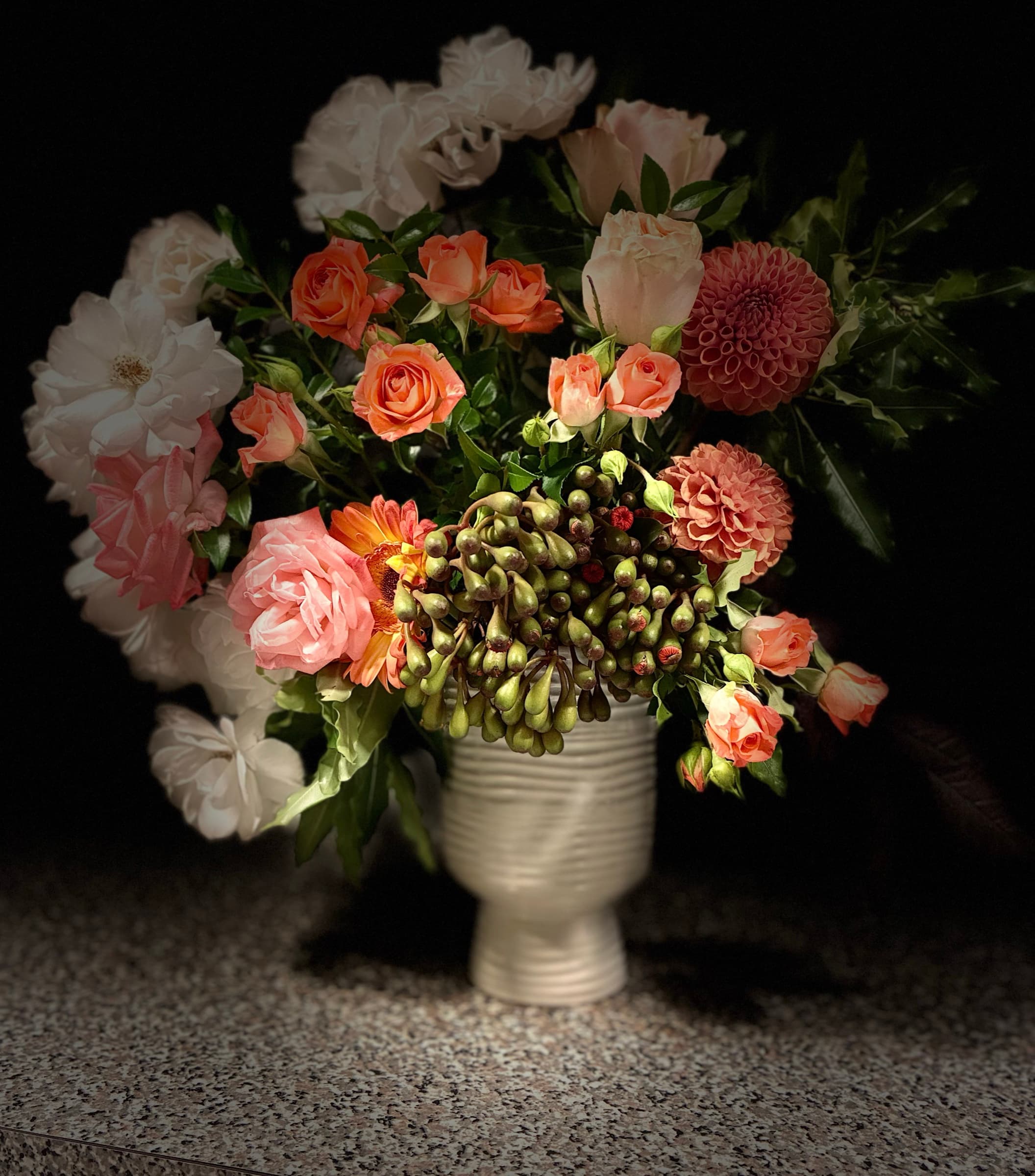 Coral roses and dahlias in a white ceramic urn