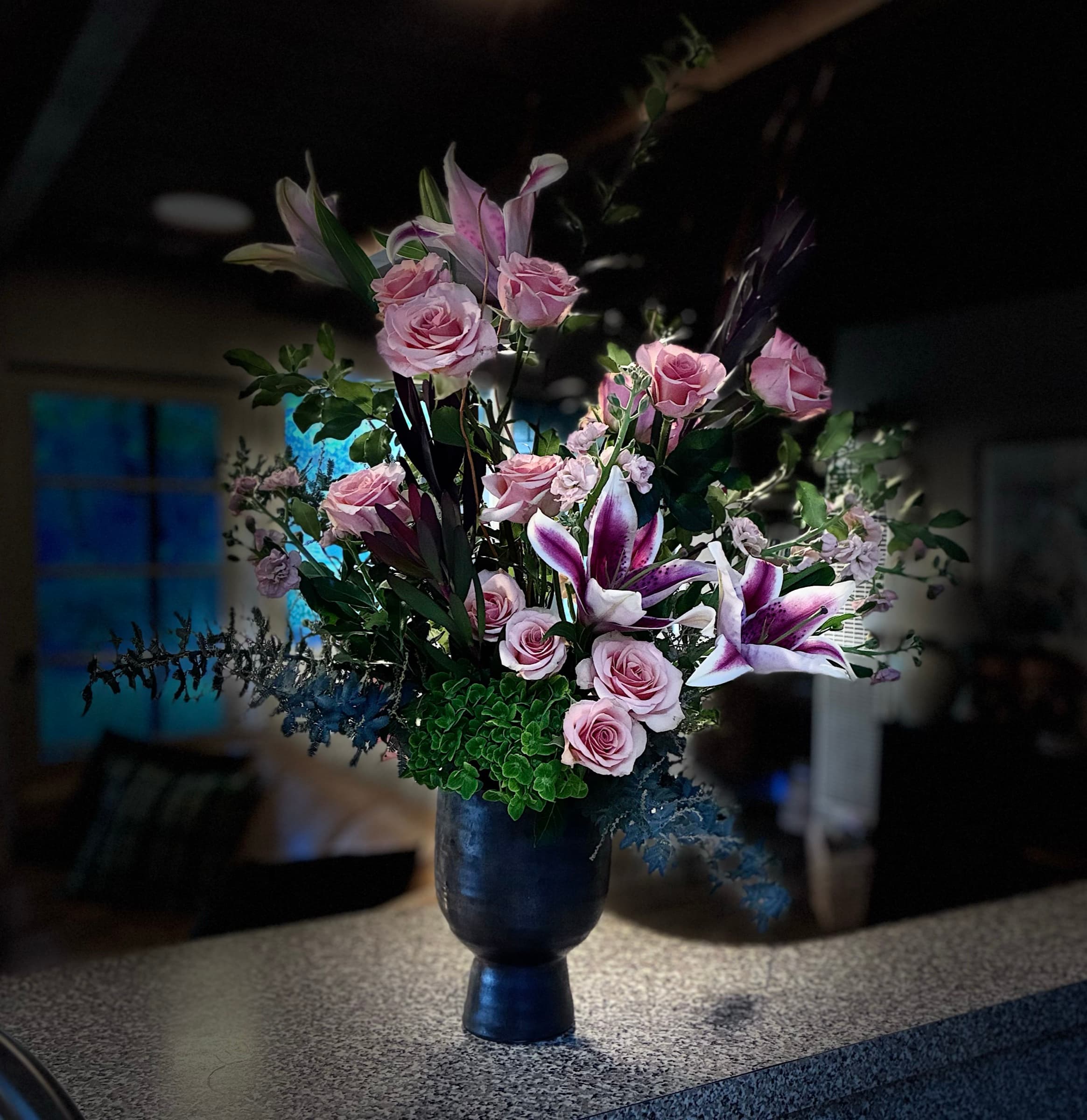 Stargazer lilies and pink roses in a navy urn